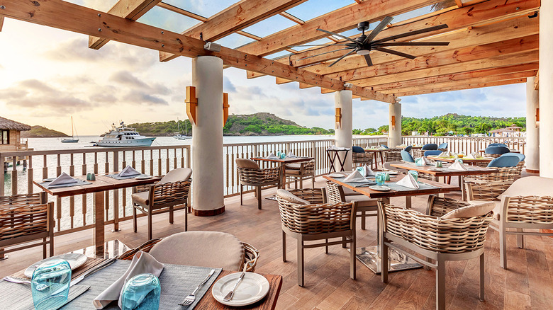 Exterior view of Grazie Italian Trattoria, one of the eight restaurants at the Royalton Antigua, a five-star resort, with green hills and boats on Antigua's Deep Bay in the background
