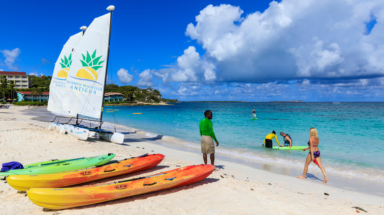 Sea kayaks and small catamarans on a white sand beach with turquoise water