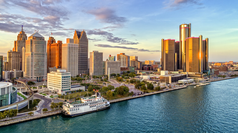 A aerial shot of Detroit's downtown skyscrapers and parks along Lake Erie during sunset.