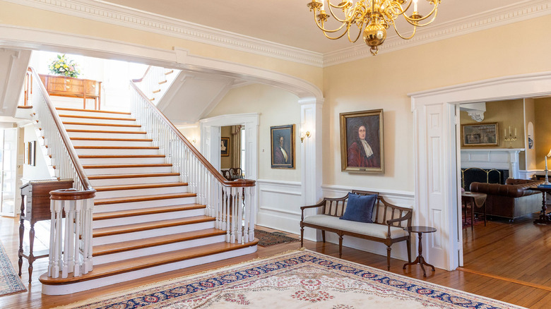 Interior of the Inn at Warner Hall with hand-painted portraits hanging on the walls with a grand staircase in the middle of the room.