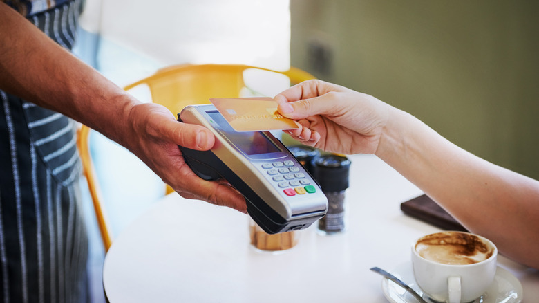 A hand paying for a purchase with a credit card