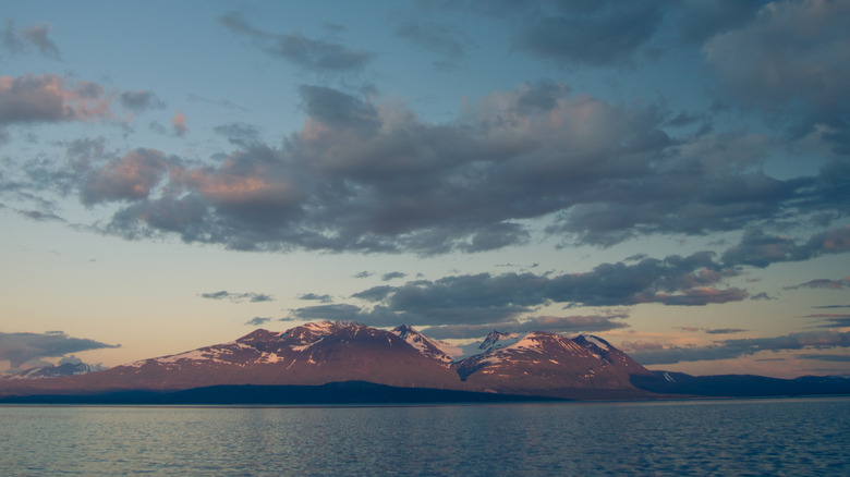 Mountains capped with snow loom high above the calm waters of Lake Akkajaure