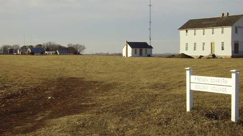 green greass with white sign and white building under blue sky