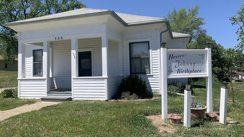 white house and white sign on green grass under blue sky