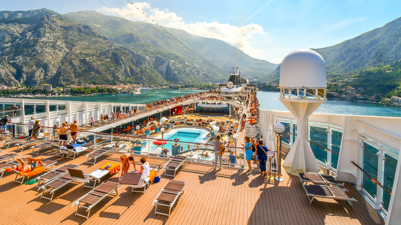 The sun deck of an MSC cruise ship has pools and deck chairs, while coastal mountains rise in the distance