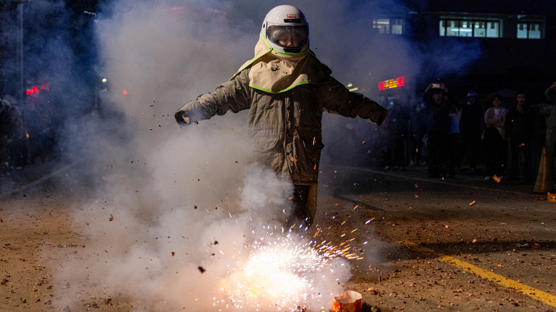 Woman wearing helmet lights firecracker