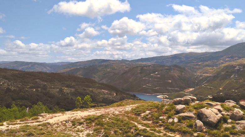 View of green hills, boulders, and a lake near Fafião, Portugal