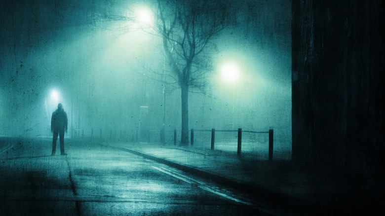 Moody figure standing on a street at night