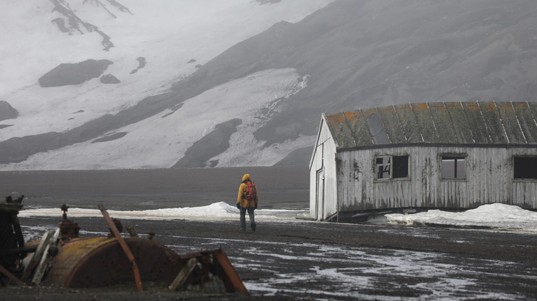 A tourist walks alone by the ruins of a whaling station in Whalers Bay on Deception Island, Antarctica