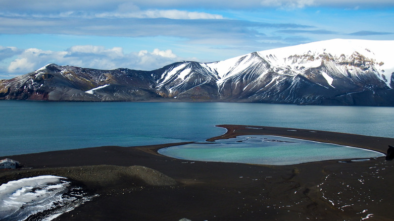 The snow-covered mountains and clear blue waters of Deception Island in Antarctica