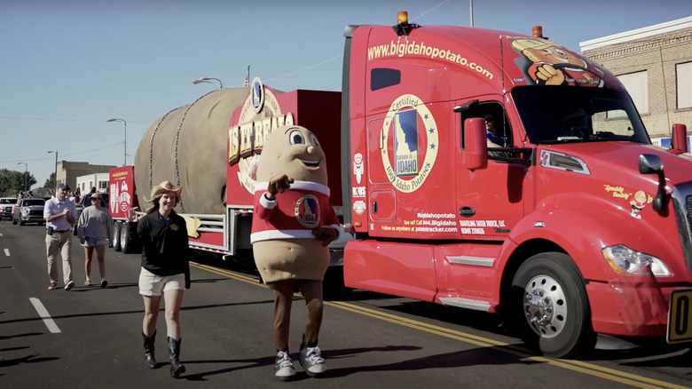 Woman walking alongside spud mascot and potato truck