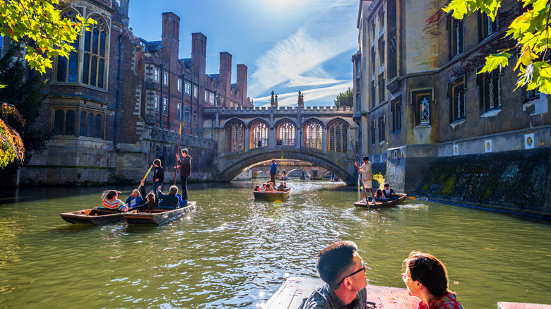 Several punting boats on the river under a medieval building