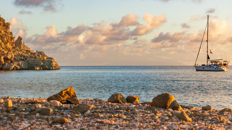 Rocky beach in St. Barts and a boat sailing on the water