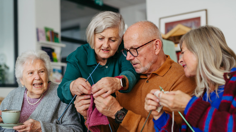 Group of senior people learning knitting together with a tutor in a community center