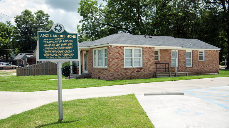 Blue sign reading "Amzie Moore Home" and brick house