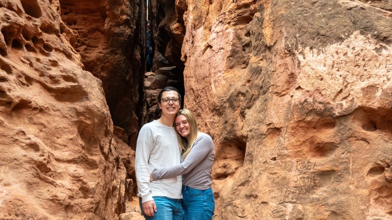 A couple smiles in front of the Crack at Pioneer Park in St. George, Utah