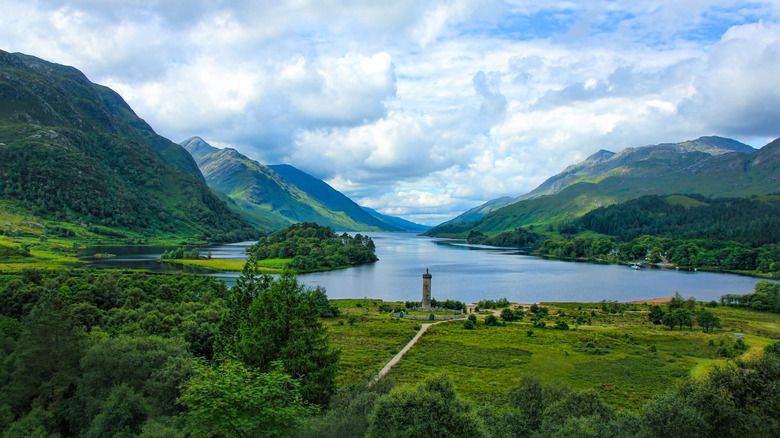 The Glenfinnan Monument sits beside a loch, surrounded by mountains, on the Cape Wrath Trail