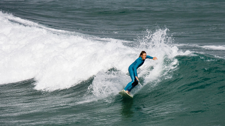 A surfer catching a breaking wave at Fistral Beach in Newquay, England