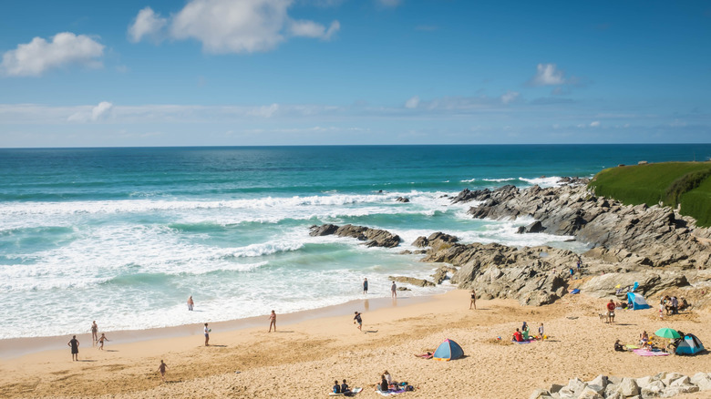 Beachgoers sprawled along the sandy shores of Fistral Beach in Cornwall, England
