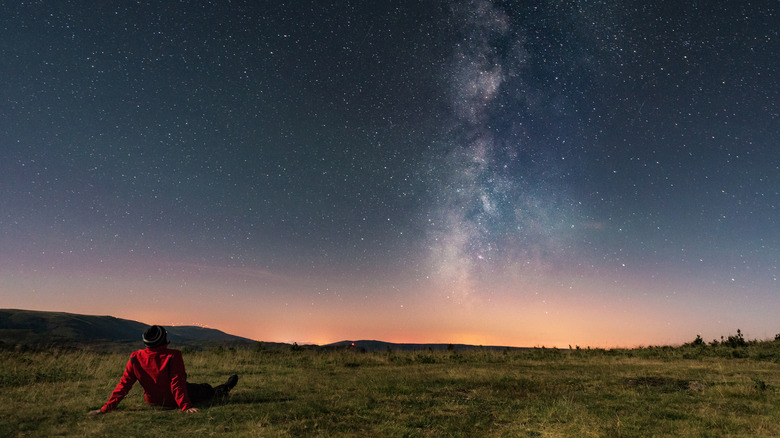A person watching the stars and the Milky Way from an open field