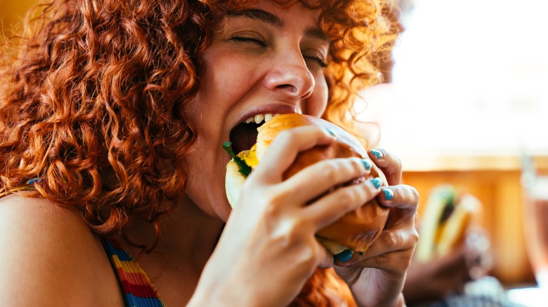 Woman biting into hamburger