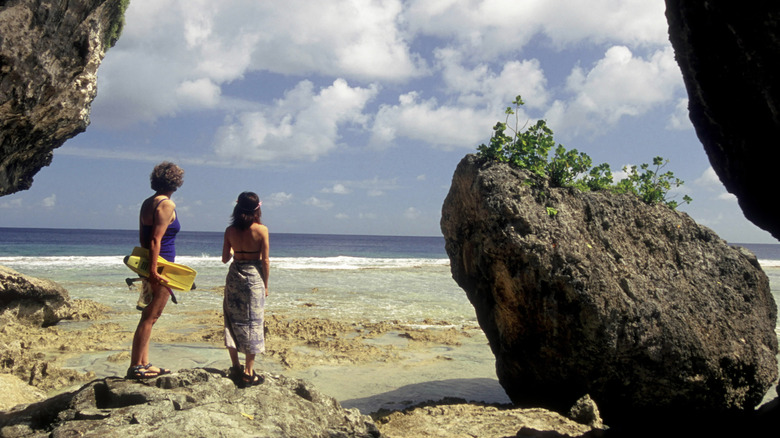 Two people prepare to snorkel from the rocky shoreline of Niue