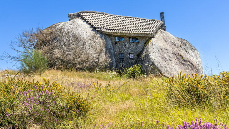 House with roof and windows between two giant boulders