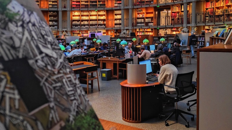 A book in the foreground with walls of books in the backdrop