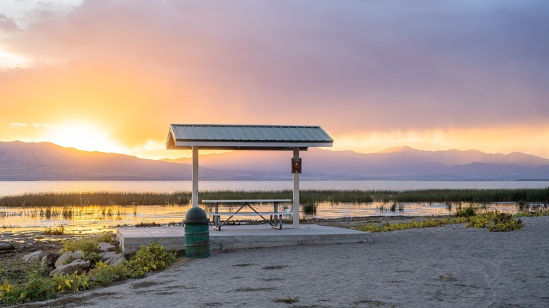 A covered picnic table faces the lake and mountains at Vineyard Beach, Utah