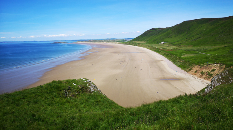 Green coastal hills back a long sandy beach at Llangennith, Wales