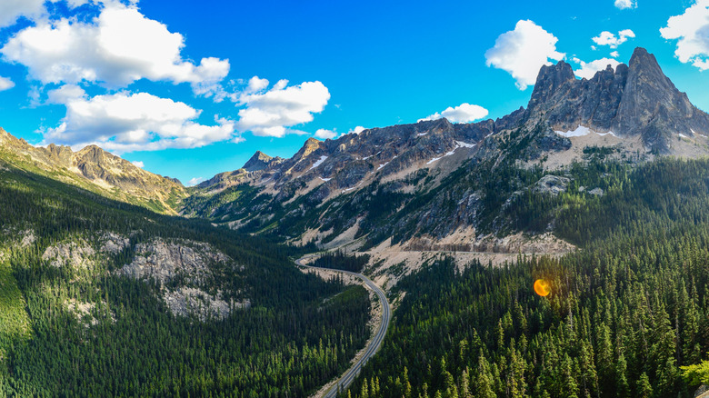 A long road winds through mountainous forested terrain
