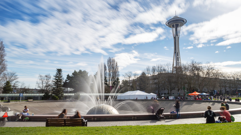 People sit on park benches near the International Fountain in Seattle