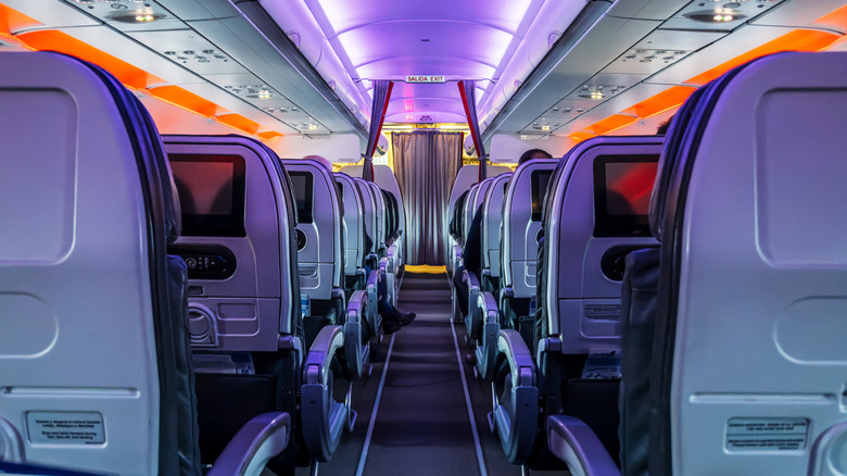 Airplane cabin lit with purple and orange lights