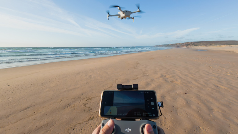 Person flying a drone over a beach