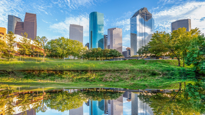 Park with paved trail and lake in Houston, Texas with skyline visible.