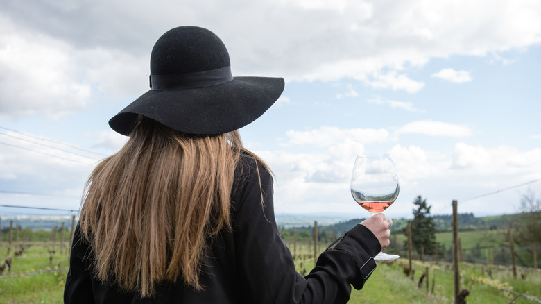 Woman holding a glass of wine in a vineyard