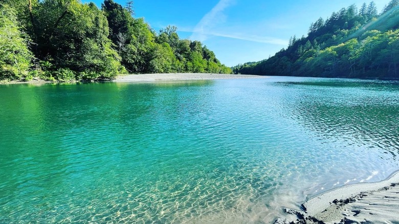 Turquoise river blue sky green trees on banks