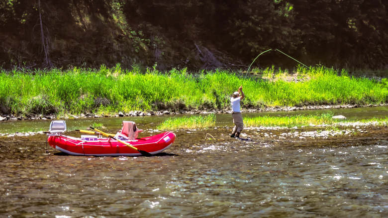 A man fishes next to a red raft on the Wallowa River in eastern Oregon
