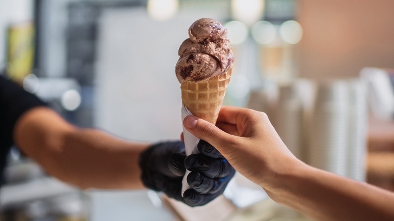 Vendor handing ice cream cone to customer