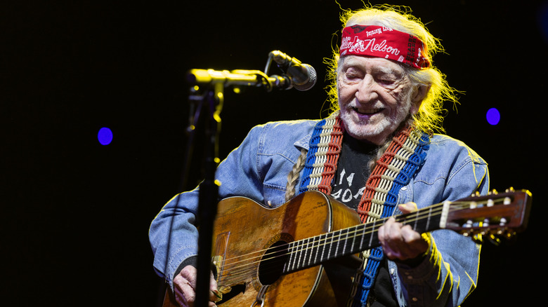 A 92-year-old Willie Nelson playing guitar on stage during the Luck Reunion festival in 2026.