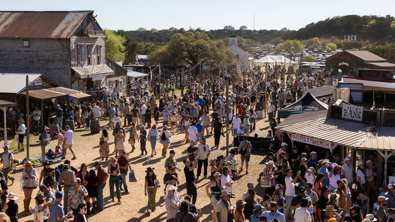 Crowds of people gathered in a Wild West town with authentic buildings during the Luck Reunion music festival.