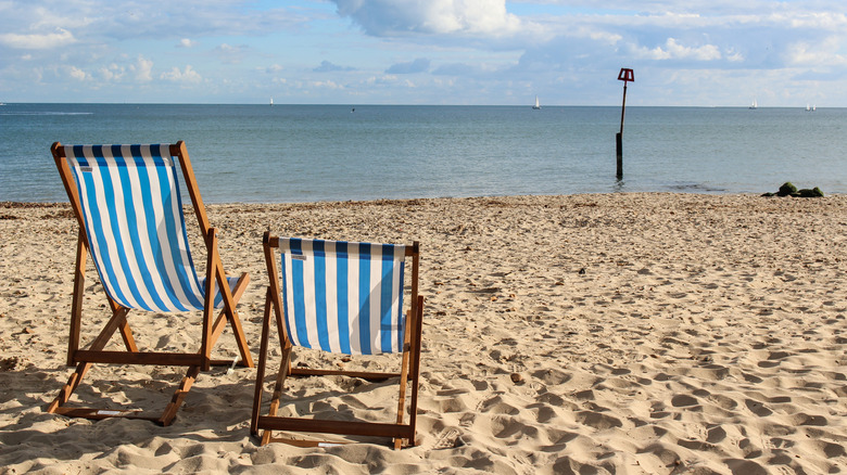 Two blue and white-striped beach chairs sit on the sand at Avon beach