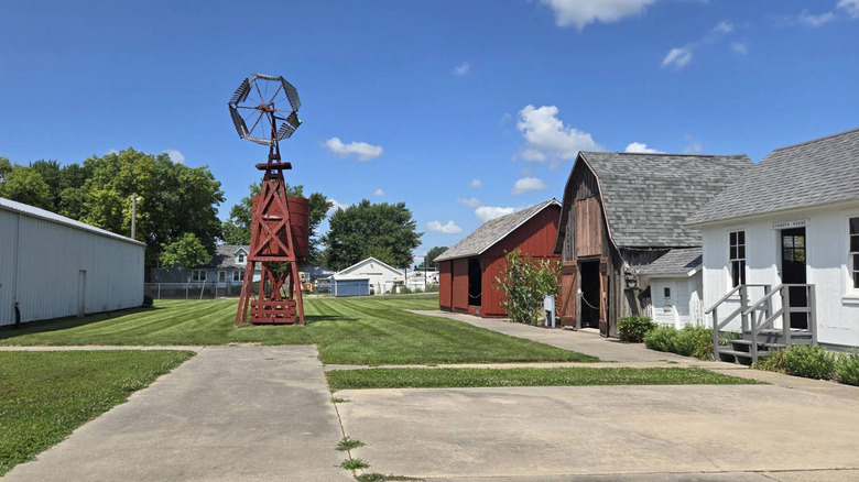 Historic buildings and windmill in Kalona Historic Village on clear summer day.