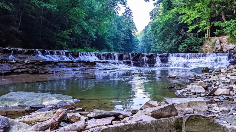 View of a roaring, tiered waterfall with a rocky creek bed in a wooded area at South Chagrin Reservation in Ohio.