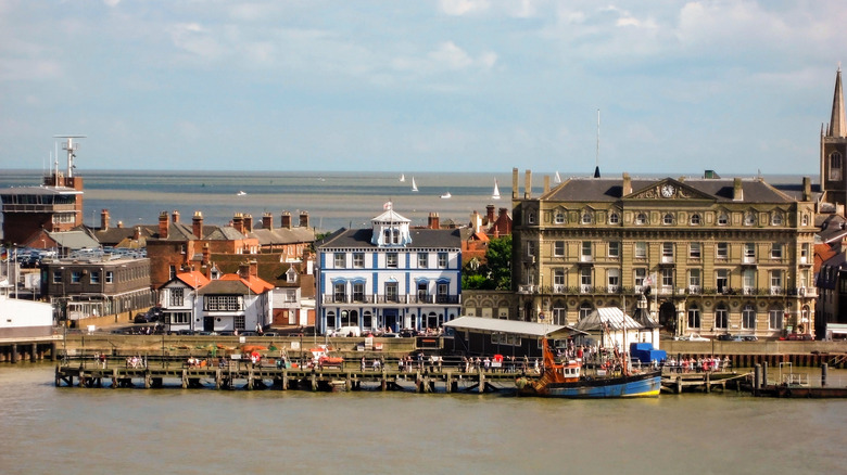 Historic buildings, a fishing vessel, and sailing boats by the seafront in Harwich, England