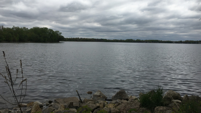 Flat and calm water from a rocky shoreline at Lake Kegonsa State Park on a cloudy day