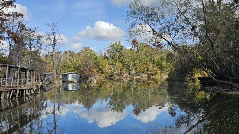 Still marshland water with vegetation, small wooden buildings and clear skies