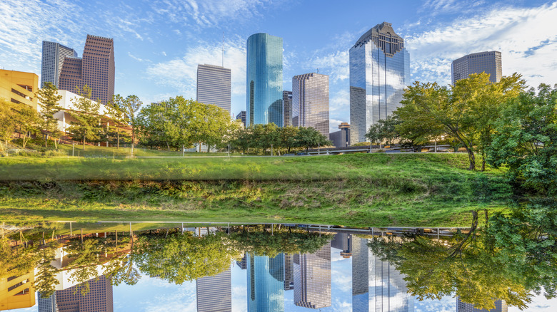 Houston's downtown skyline glows in morning light, mirrored perfectly in Buffalo Bayou's calm waters