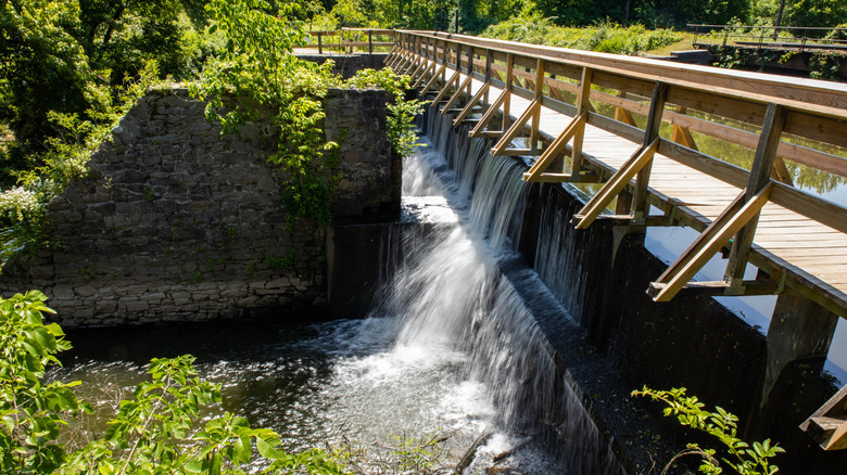 The Alexauken Creek Aqueduct cascading water beside rock walls and green foliage.