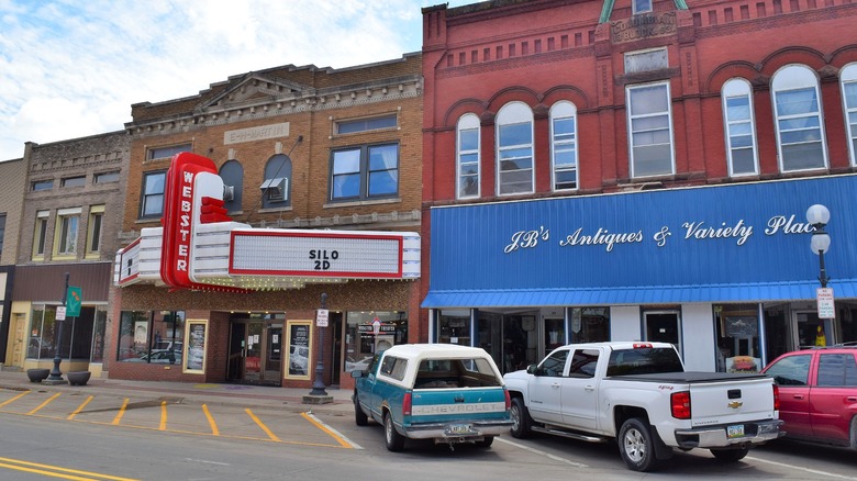 Downtown Webster City featuring old brick buildings with the theatre and an antique store with a few vehicles parked on the street